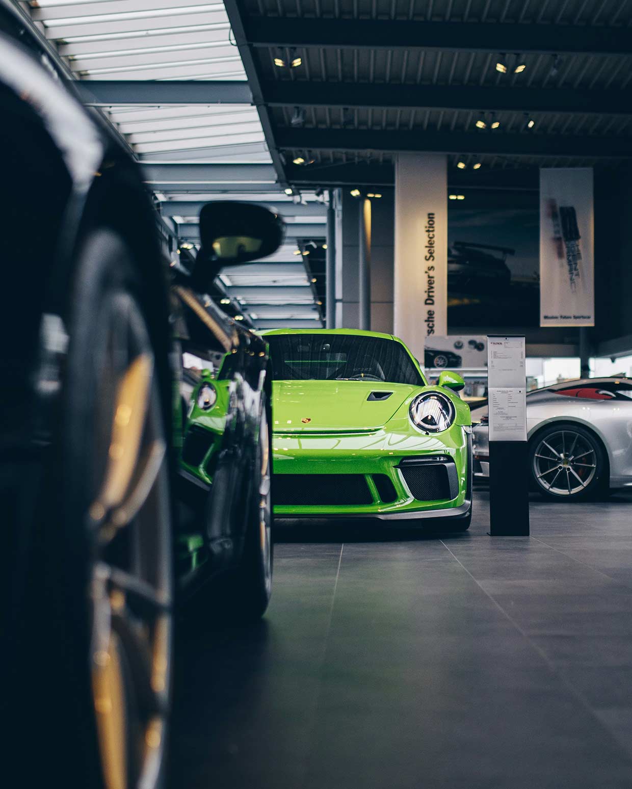 Grüner Porsche als Blickfang im Showroom mit schwarzem Porsche halb im Vordergrund
