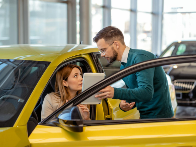 Autohaus-Mitarbeiter berät Kundin im Fahrzeug mit Tablet zur Optimierung von Customer Journey und CRM-Prozessen
