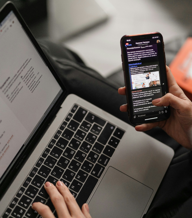 Person nutzt Smartphone und Laptop parallel für digitale Kommunikation, mobile Kampagnensteuerung und CRM-basiertes Marketing im Autohaus